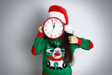 Girl in Santa hat with clock on white background. New Year countdown