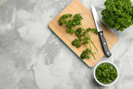 Fresh curly parsley, cutting board and knife on gray table, flat lay. Space for textの写真素材