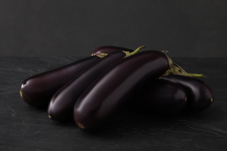 Pile of raw ripe eggplants on black tableの写真素材