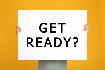 Man holding poster with text Get Ready? on yellow backgroundの写真素材