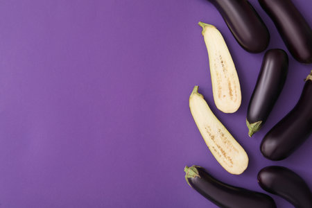 Raw ripe eggplants on violet background, flat lay. Space for textの写真素材