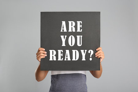 Man holding poster with text Are You Ready? on light gray background