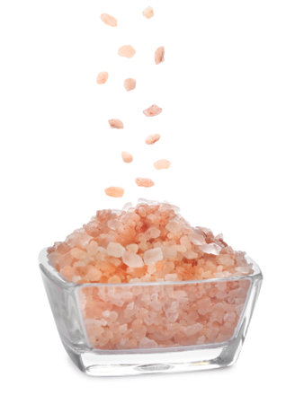 Pink himalayan salt falling into bowl on white backgroundの写真素材