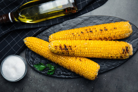 Fresh grilled corn cobs on gray table, flat lay