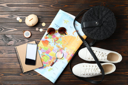World map and items on wooden background, flat lay. Travel during summer holidaysの写真素材