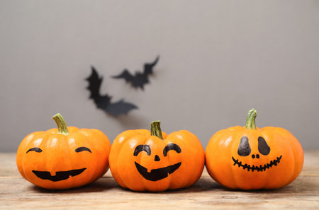 Pumpkins with scary faces near decorative bats on gray background, space for text. Happy Halloweenの写真素材