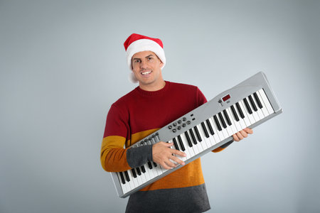 Man in Santa hat playing synthesizer on light gray background. christmas musicの写真素材