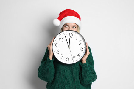 Woman in Santa hat with clock on white background. New Year count downの写真素材