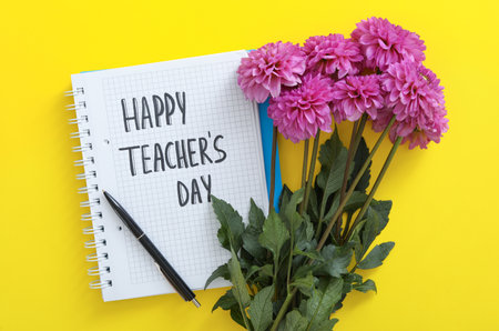 Beautiful flowers and notebook with words HAPPY TEACHER'S DAY on yellow background, flat layの写真素材