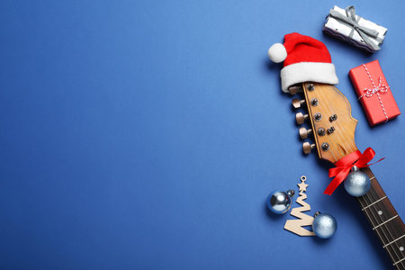 Flat lay composition with guitar and Santa hat on blue background, space for text. christmas musicの写真素材