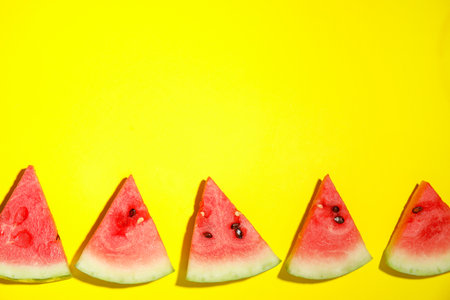 Watermelon slices on yellow background, flat lay. Space for text