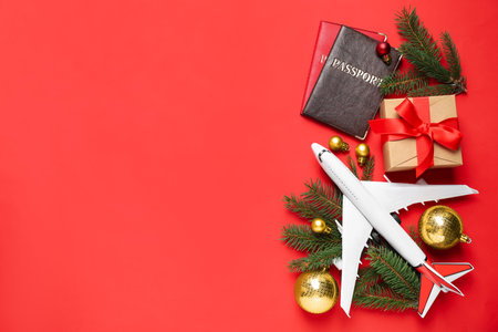 Flat lay composition with Christmas decorations, toy airplane and passports on red background, space for text. winter holidaysの写真素材
