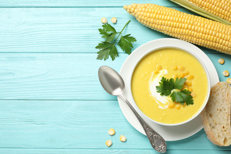 Delicious creamy corn soup served on turquoise wooden table, flat lay. Space for textの写真素材