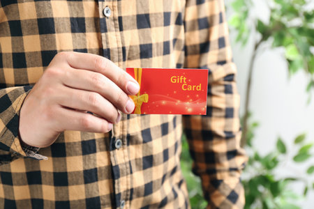 Man with gift card on blurred background, closeupの写真素材