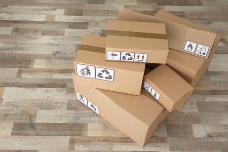 Cardboard boxes with different packaging symbols on floor. Parcel delivery