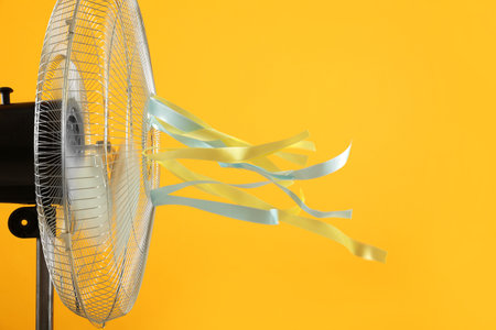 Electric fan on yellow background. summer heatの写真素材