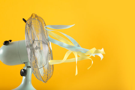 Electric fan on yellow background. summer heatの写真素材