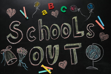 Pieces of chalk, stationery and text SCHOOL'S OUT written on blackboard, flat lay. summer holidays