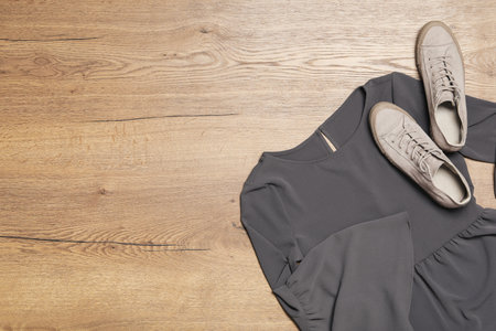 Stylish gray dress and shoes on wooden background, flat lay. Space for text