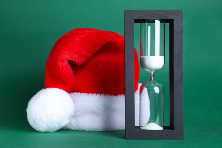 Hourglass and Santa hat on green background. christmas count downの写真素材