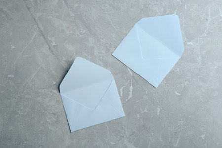 White paper envelopes on gray marble background, flat lay