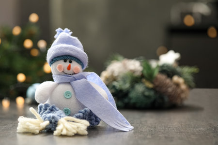 Snowman toy on gray table against blurred festive lights, space for text. christmas decorationの写真素材
