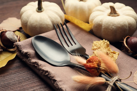 Autumn table setting, closeup, Cutlery with pumpkins and fallen leaves on wooden tableの写真素材