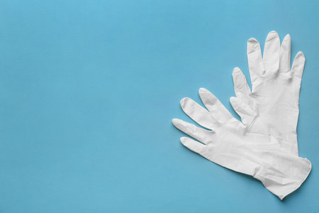 Pair of medical gloves on blue background, flat lay. Space for textの写真素材