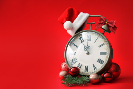 Alarm clock and festive decor on red background, space for text. New Year count downの写真素材