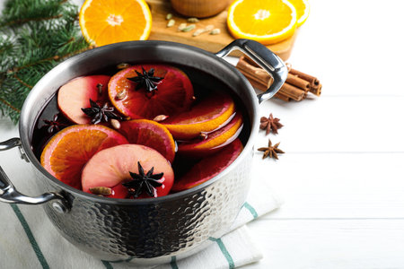 Delicious mulled wine and ingredients on white wooden tableの写真素材