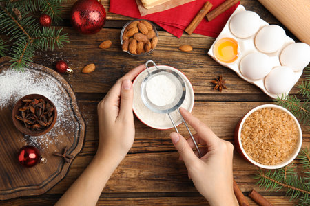 Woman cooking traditional Christmas cake on wooden table with ingredients, top viewの写真素材