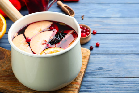 Delicious mulled wine and ingredients on blue wooden table, closeup. Space for textの写真素材