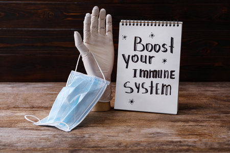 Notebook with Phrase Boost Your Immune System and medical items on wooden tableの写真素材