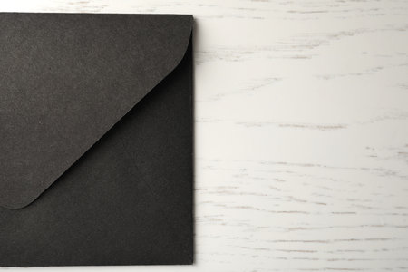 Black paper envelope on white wooden background, top view. Space for textの写真素材