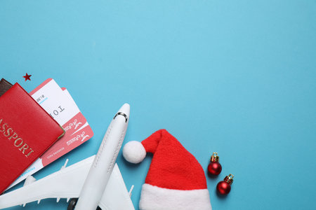 Santa hat, toy airplane, passports with airline tickets and space for text on blue background, flat lay. christmas holidaysの写真素材