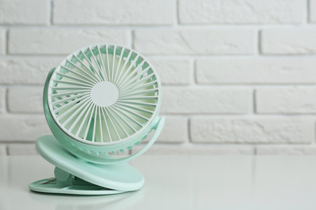 Portable fan on table near white brick wall, space for text. summer heatの写真素材