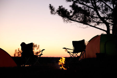 Camping tents and chairs in wilderness at sunsetの写真素材