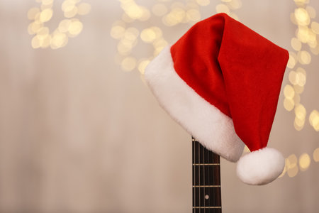 Guitar with Santa hat against blurred lights, space for text. christmas musicの写真素材
