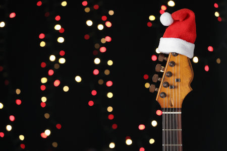 Guitar with Santa hat against blurred lights, space for text. christmas musicの写真素材