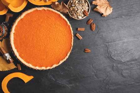 Flat lay composition with delicious homemade pumpkin pie on black table. Space for textの写真素材