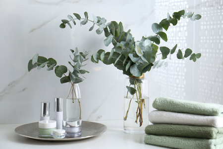 Fresh eucalyptus branches and cosmetic products on countertop in bathroomの写真素材