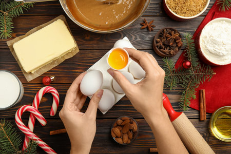 Woman cooking traditional Christmas cake on wooden table with ingredients, top viewの写真素材