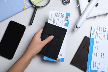 Woman with passport and airline ticket at white table, top view. travel agency concept