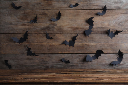 Empty wooden table near wall decorated with paper bats. halloween celebrationの写真素材