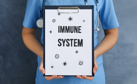 Woman holding clipboard with phrase Immune System on blue background, closeupの写真素材