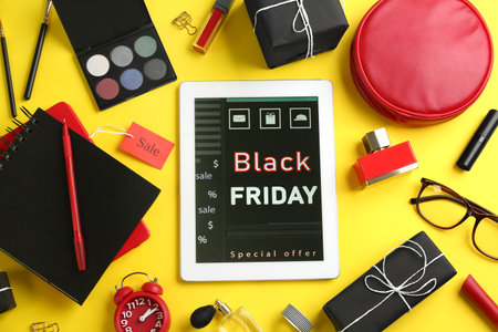 Flat lay composition with tablet, gifts and accessories on yellow background. black friday saleの写真素材