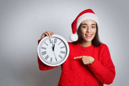 Woman in Santa hat with clock on white background, space for text. New Year count downの写真素材