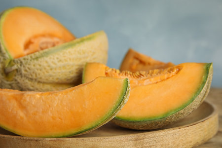 Tasty fresh cut melons on wooden tray, closeup