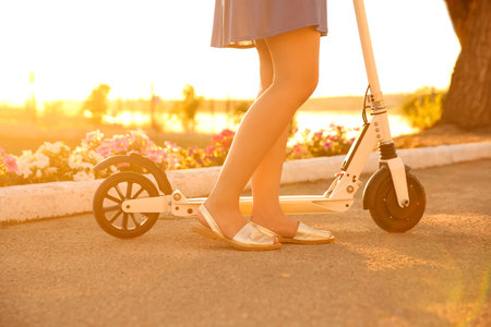 Woman riding electric kick scooter outdoors on sunny day, closeupの写真素材