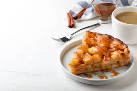Slice of traditional apple pie served with coffee on white wooden table. Space for textの写真素材